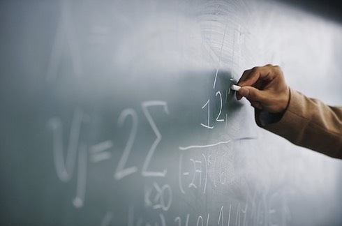 Teacher Writing a Formula on a Blackboar