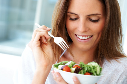 Happy young lady eating fruit salad